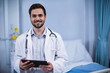 © WavebreakMediaMicro - Male doctor wearing lab coat and stethoscope, holding digital tablet in hospital room