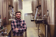 © WavebreakMediaMicro - Standing male in his twenties crossing arms at industrial brewery, with fermentation tanks