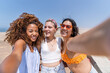 © Guillermo Spelucin - Multi ethnic friends taking a selfie on a beach adventure trip