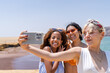 © Guillermo Spelucin - Multiracial friends taking selfie on sunny beach during adventure trip