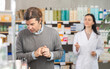 © JackF - Male customer looking for something in a drugstore. Female pharmacist offers him medicines