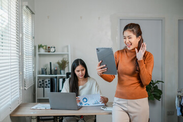Wall Mural - two women working together in a modern office, using technology and reviewing documents, showcasing 