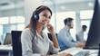 © SOEM - A smiling customer service representative wearing a headset, working at a desk in a modern office with a computer and other employees in the background.