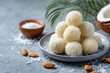© TuruMuru - Coconut sweets made with condensed milk on a plate against a concrete backdrop Indian dessert Coconut Ladoo