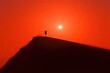 © isti - Lone figure stands atop a dune silhouetted against a fiery sunset, creating a sense of solitude and vastness