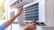 © nuttachet chinavong - Efficient technician adjusting air conditioning unit with remote control, ensuring optimal cooling and comfort in modern environment