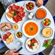 © Jessica - Mediterranean appetizers table concept. Diner table with tapas selection: cured meat and salami, gazpacho soup, jamon, olives, cheese, hummus and vegetables.   Overhead view.