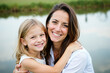 © Creuxnoir - Mother and daughter hugging each other in front of a lake.