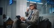 © Framestock - Airport Terminal: Successful Entrepreneur Using Digital Tablet and Drinking Coffee, Doing e-Business. Businessman Remote Work Online Waiting for Flight in Departure Lounge. Slow Motion, Medium Shot.