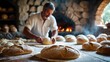 © JuliaM - Baker prepares Rustic Bread near Oven. Fresh loaves on table.