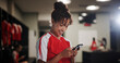 © peopleimages.com - Sport, girl and smile in locker room with mobile, social media and check training schedule. Football player, woman and happy with phone for good news, league acceptance or favorite soccer team update