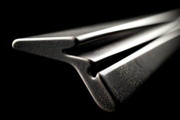Leinwandbilder - Close-up view of a sleek metal tool reflecting light in a dark setting highlighting its sharp edges and contours