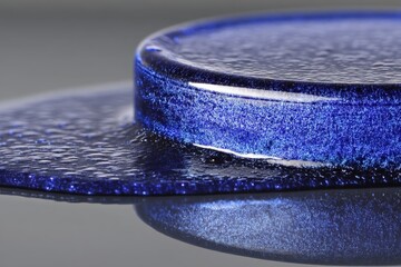 Leinwandbilder - Close-up of a melting blue resin in an artistic arrangement on a reflective surface during daylight