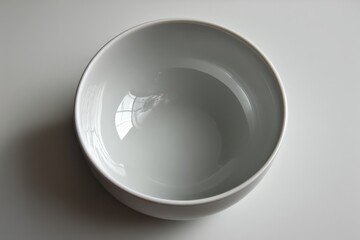 Leinwandbilder - Simple white ceramic bowl on a smooth surface with reflections seen in the interior and soft light illuminating the scene