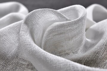 Poster - Delicate white fabric drapes beautifully on a textured surface in soft light showcasing intricate patterns