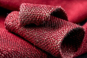 Poster - Textured red fabric rolls showcasing woven patterns and rich hues in natural light