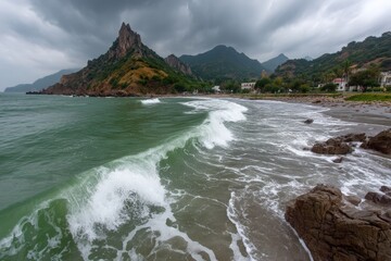 Aufkleber - Waves crash on a rocky shore beneath overcast skies in a coastal landscape at midday