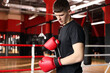 © New Africa - Man putting on protective boxing gloves in training center. Space for text