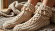 © Angavlan - Cozy girl wearing knitted socks relaxing at home on a warm blanket