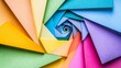 © acoustIcara - This abstract close-up image shows vibrant colorful paper folded into a mesmerizing geometric spiral pattern featuring intricate texture.