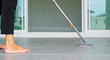 © sorapop - Woman mops the indoor floor, cleaning the front area of her home with a mop and rag. Housewife dedicated to maintaining cleanliness. Represents professional housekeeping and house maintenance concepts
