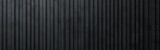 Dark textured vertical metal panels with slight variations in color and surface texture creating an industrial and modern aesthetic