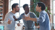© Prostock-studio - Office conflict. Angry multiracial young men fighting at workplace, afro guy standing between them