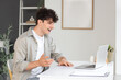 © Pixel-Shot - Young man video chatting with laptop on table at home