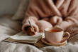 © Centric  - Woman enjoying a quiet morning in bed, writing in her personal journal while sipping a warm cup of tea, creating a cozy and relaxing atmosphere
