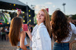 © artiemedvedev - Women enjoy drinks at beach music fest, friends gather for fun, dance, summer vibes. Sunset party atmosphere, celebrate festival season with cold beverages, sea backdrop.