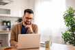 © Dorde - Man with Glasses Working on Laptop at Sunlit Kitchen Table with Green Plant Background