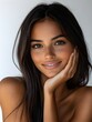 © CHAIYAPHON - A beautiful young woman with long dark hair and tan skin smiles gently while resting her hand on her chin.