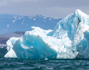 Wall Mural - Majestic ice formations rise from ocean, showcasing stunning shades of blue against backdrop of rugged mountains. serene landscape evokes sense of tranquility and wonder