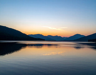 Wall Mural - serene sunset over calm lake, reflecting vibrant colors of sky and surrounding mountains. tranquil scene evokes sense of peace and natural beauty