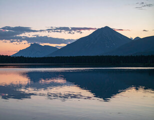 Wall Mural - Majestic mountains reflect in calm lake during sunset, creating serene and picturesque landscape. vibrant colors of sky enhance tranquil atmosphere of this natural scene