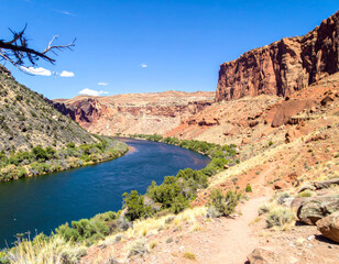 Wall Mural - stunning landscape featuring vibrant blue river flowing through rugged canyon, surrounded by rocky cliffs and lush greenery. scene evokes sense of tranquility and natural beauty