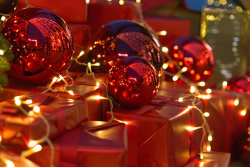 Wall Mural - new year gifts in red paper and red toy balls, lights bokeh in the background, merry christmas, shal