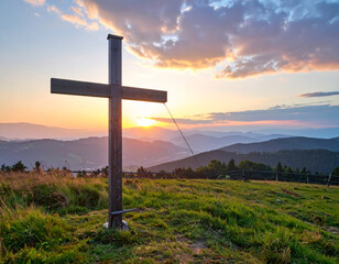 Wall Mural - scenic view of wooden cross at sunset, surrounded by lush green hills and mountains. sky is painted with vibrant colors, creating serene and peaceful atmosphere