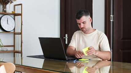 Bearded man sticks a note on his laptop.