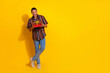 © deagreez - Young man holding a red gift box while smiling against a vibrant yellow background expressing joy and excitement