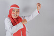 © Alpian Ahmad Nurdin - Indonesian Muslim woman with red headscarf and face paint celebrating independence with joyful expression and victorious pose raising fist in patriotic spirit