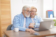 © New Africa - Senior man and mature woman watching something on laptop at home. Happy couple