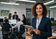 © Muaz - Smiling businesswoman holding tablet in modern office with team collaborating