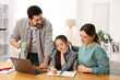 © New Africa - Parents helping their daughter with homework at wooden table indoors