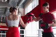 © New Africa - Woman in protective gloves having boxing practice with her coach at training center