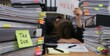 © TanTin - 'Tax Due' sticky note on folders, blurred backdrop with tired employee buried under paperwork with help sign, burnout, deadline stress, lack of balance in tax season, workplace exhaustion, overload