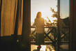 © olezzo - Young woman standing on balcony and admiring view of sunset or sunrise in mountains