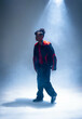 © Wavebreak Media - Standing African American male wearing black and red jacket on smoky stage, with spotlight beam