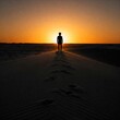 © Andbiz - A lonely man stands on top of a dune at sunset.