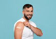 © Prostock-studio - Smiling adult attractive caucasian guy show shoulder with band aid after vaccination, isolated on blue background. Health care, vaccine against flu and covid-19 virus, immunization of population